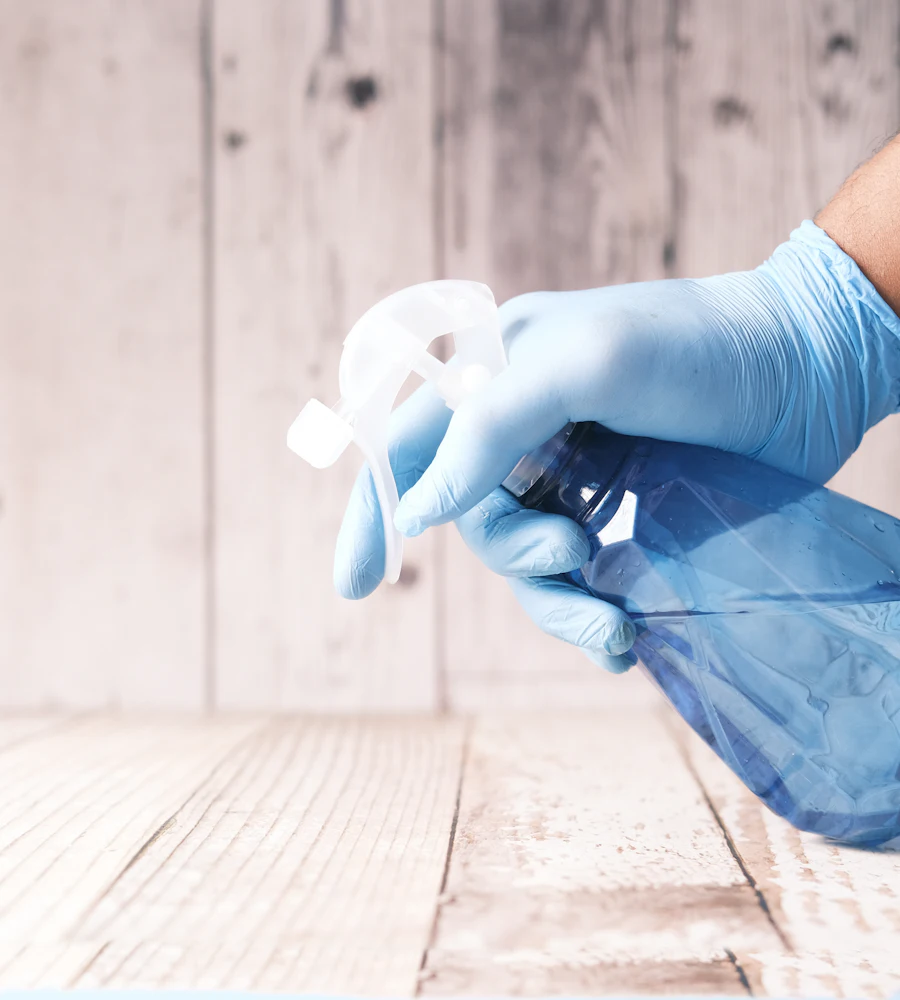Gloved hand holding a cleaning spray bottle